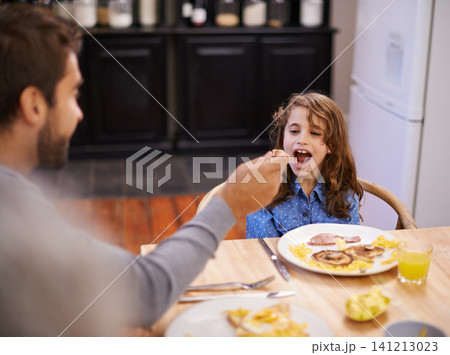 Dad, feeding and girl eating breakfast on table at home kitchen for health, nutrition and wellness. Child, father and happy for food in family house together for morning meal, development and diet 141213023