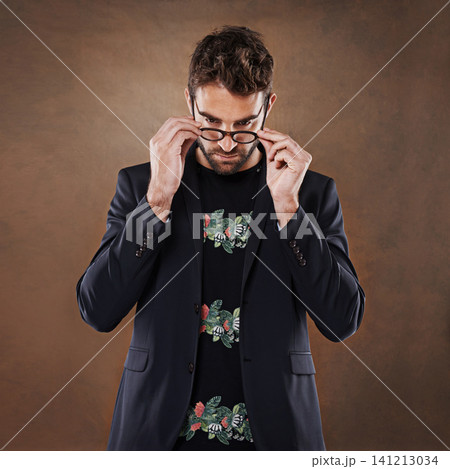 Glasses, fashion and man in studio with blazer for classy, stylish and trendy outfit with confidence. Spectacles, serious and male person with elegant and fancy style isolated by brown background. Glasses, fashion and man in studio with blazer for classy, stylish and trendy outfit with confidence. Spectacles, serious and male person with elegant and fancy style isolated by brown background. 141213034