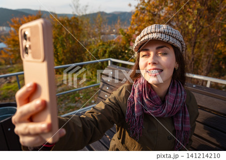 Woman taking selfie smiling in autumn park Woman taking selfie smiling in autumn park 141214210