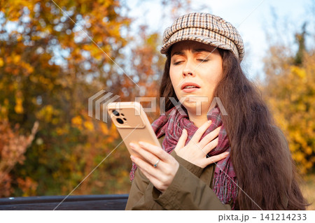 Woman with eyes closed looking at phone Woman with eyes closed looking at phone 141214233