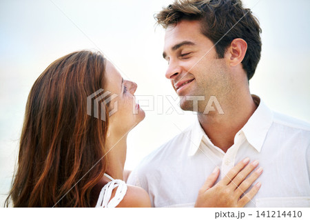 Couple, outdoor and smile with love, sky and eye contact on summer holiday with connection in nature. Man, woman and trust for bonding, romance or relationship with memory on vacation in Mykonos 141214410