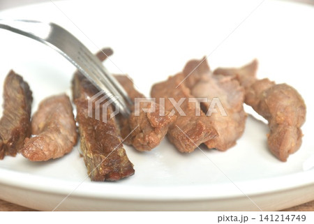 fried crispy salty fermenting beef fat meat with pepper stabing by fork on plate fried crispy salty fermenting beef fat meat with pepper stabing by fork on plate 141214749