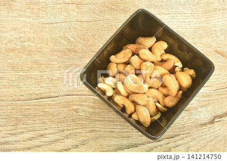 roasted salty cashew nuts arranging in black square cup on table 141214750