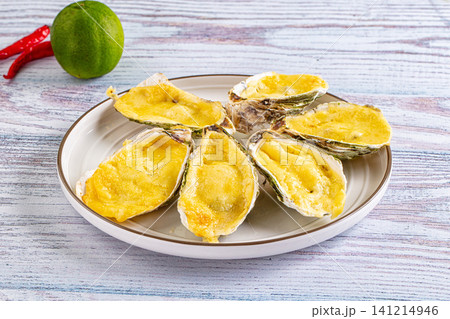 Baked oysters with cheese on white plate with lime and chili Baked oysters with cheese on white plate with lime and chili 141214946