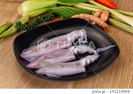 Fresh squid on black plate with herbs and vegetables Fresh squid on black plate with herbs and vegetables 141214949