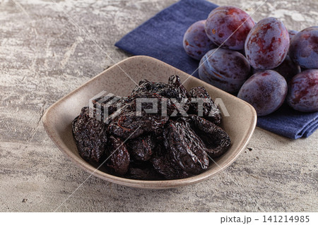 Dried plums in ceramic bowl with fresh plums on blue napkin Dried plums in ceramic bowl with fresh plums on blue napkin 141214985