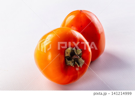 Two ripe persimmons on white textured surface Two ripe persimmons on white textured surface 141214999