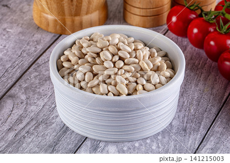 White beans in ceramic bowl with tomatoes and wooden grinders on rustic table White beans in ceramic bowl with tomatoes and wooden grinders on rustic table 141215003