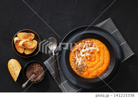 spiced sweet potato soup in a black bowl spiced sweet potato soup in a black bowl 141215336