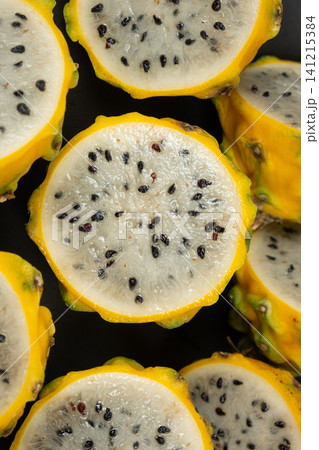 Halved yellow dragon fruit showing white flesh and black seeds Halved yellow dragon fruit showing white flesh and black seeds 141215384