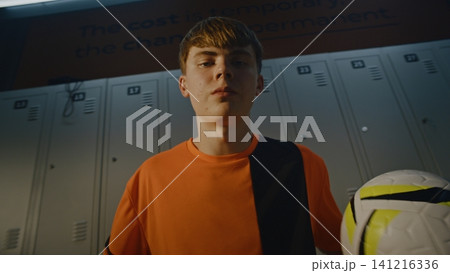 Proud Youth Athlete Tossing Soccer Ball from Hand to Hand in Dressing Room Proud Youth Athlete Tossing Soccer Ball from Hand to Hand in Dressing Room 141216336