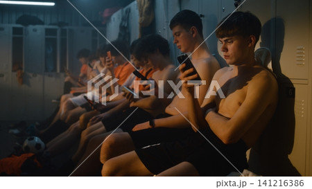 Teenage Football Teammates Taking Well Earned Break after Practice inside Locker Room Teenage Football Teammates Taking Well Earned Break after Practice inside Locker Room 141216386