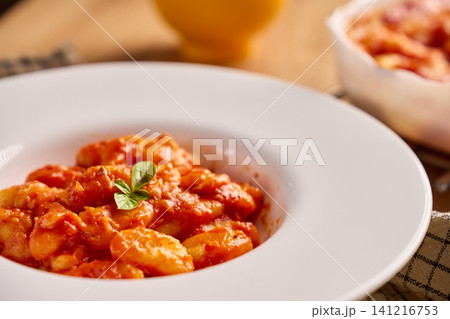 Gnocchi in tomato sauce served with fresh basil on plate Gnocchi in tomato sauce served with fresh basil on plate 141216753