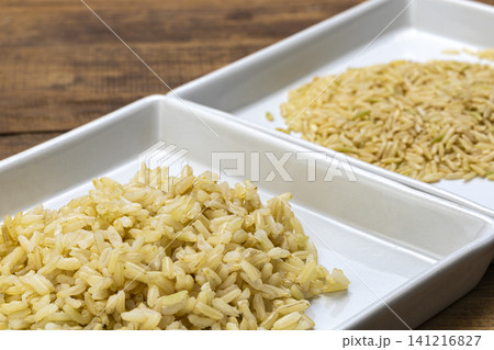 Close-Up Comparison of Cooked and Raw Brown Jasmine Rice Portions Arranged Side by Side in a Divided White Ceramic Tray on Rustic Wooden Surface 141216827