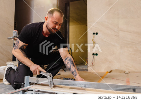 Construction worker cutting ceramic tile using manual tile cutter Construction worker cutting ceramic tile using manual tile cutter 141216868