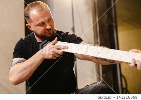 Construction worker checking ceramic tile before cutting it with tile cutter Construction worker checking ceramic tile before cutting it with tile cutter 141216869