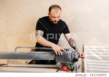 Construction worker using tile saw cutting machine preparing ceramic tiles for bathroom renovation Construction worker using tile saw cutting machine preparing ceramic tiles for bathroom renovation 141216878