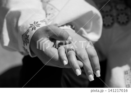 Close up of a man holding a woman hand with wedding ring in black and white traditional clothing Close up of a man holding a woman hand with wedding ring in black and white traditional clothing 141217016