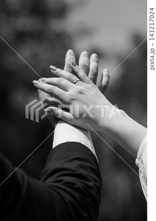 Couple holding hands with engagement ring in black and white cinematic style outdoors. Couple holding hands with engagement ring in black and white cinematic style outdoors. 141217024