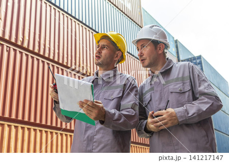 Two shipping company workers at commercial dock site. Group of male worker control loading container box from cargo freight ship for import export. Two shipping company workers at commercial dock site. Group of male worker control loading container box from cargo freight ship for import export. 141217147