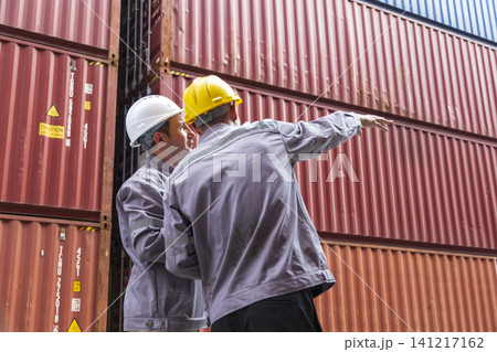 Two shipping company workers at commercial dock site. Group of male worker control loading container box from cargo freight ship for import export. Two shipping company workers at commercial dock site. Group of male worker control loading container box from cargo freight ship for import export. 141217162