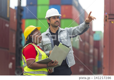 African American female and Latino male worker using tablet, checking workflow loading freight containers from Cargo freight, import export concept. African American female and Latino male worker using tablet, checking workflow loading freight containers from Cargo freight, import export concept. 141217286