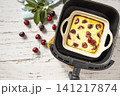 Homemade cottage cheese casserole with cherries in kitchen gadget modern air fryer on wooden background, perfect for breakfast or a snack. Top view flat lay background. Copy space. 141217874