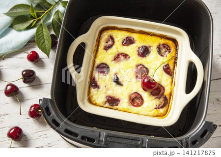 Homemade cottage cheese casserole with cherries in kitchen gadget modern air fryer on wooden background. perfect for breakfast or a snack. Homemade cottage cheese casserole with cherries in kitchen gadget modern air fryer on wooden background. perfect for breakfast or a snack. 141217875