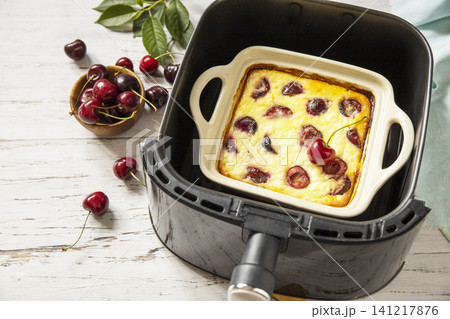Homemade cottage cheese casserole with cherries in kitchen gadget modern air fryer on wooden background. perfect for breakfast or a snack. Copy space. 141217876