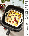 Homemade cottage cheese casserole with cherries in kitchen gadget modern air fryer on wooden background, perfect for breakfast or a snack. Top view flat lay background. 141217878