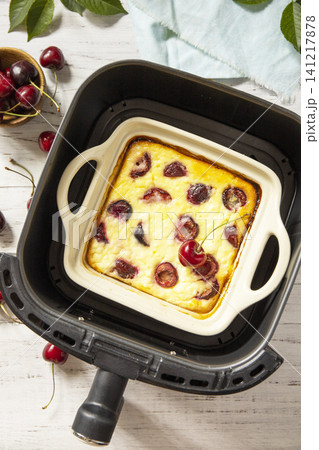 Homemade cottage cheese casserole with cherries in kitchen gadget modern air fryer on wooden background, perfect for breakfast or a snack. Top view flat lay background. Homemade cottage cheese casserole with cherries in kitchen gadget modern air fryer on wooden background, perfect for breakfast or a snack. Top view flat lay background. 141217878