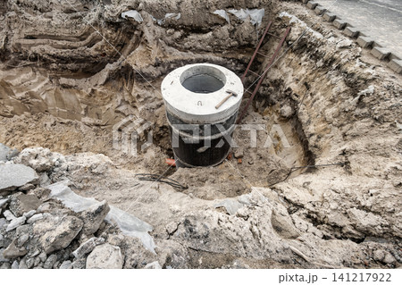Workers are constructing a concrete sewer well in a deep pit at a construction site. Tools and materials are present in the area Workers are constructing a concrete sewer well in a deep pit at a construction site. Tools and materials are present in the area 141217922