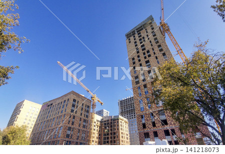 View to construction site with multiple buildings and cranes under clear blue sky View to construction site with multiple buildings and cranes under clear blue sky 141218073
