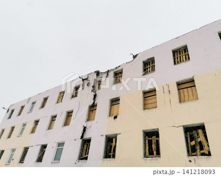 Damaged building exterior with boarded windows and visible cracks Damaged building exterior with boarded windows and visible cracks 141218093