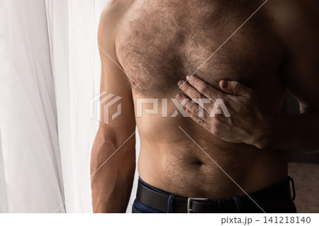 Shirtless adult man places hand over his chest in a close-up Shirtless adult man places hand over his chest in a close-up 141218140