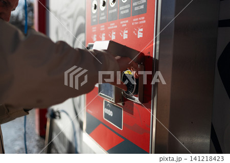 Hand pressing button on automated vending machine at manual carwash station. Hand pressing button on automated vending machine at manual carwash station. 141218423
