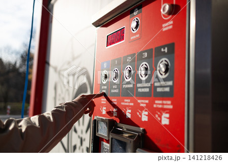Hand pressing button on automated vending machine at manual carwash station. Hand pressing button on automated vending machine at manual carwash station. 141218426