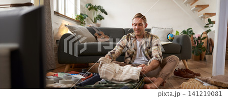 Portrait of man with suitcase, thinking what to bring on holiday, preparing for vacation, packing luggage Portrait of man with suitcase, thinking what to bring on holiday, preparing for vacation, packing luggage 141219081