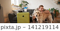 Portrait of happy young man going on holiday, travelling with his dog companion, sitting with golden retriever near suitcases and tickets 141219114