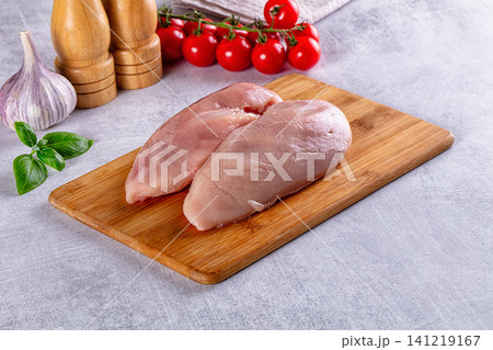 Raw chicken breasts on wooden cutting board with cherry tomatoes garlic and basil 141219167