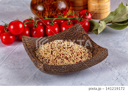 Quinoa in wooden bowl with cherry tomatoes and bay leaves on stone surface Quinoa in wooden bowl with cherry tomatoes and bay leaves on stone surface 141219172