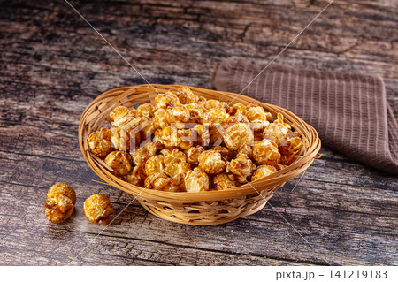 Caramel popcorn in woven basket on rustic wooden table Caramel popcorn in woven basket on rustic wooden table 141219183