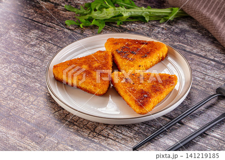 Crispy golden fried triangular food pieces on white plate with arugula Crispy golden fried triangular food pieces on white plate with arugula 141219185