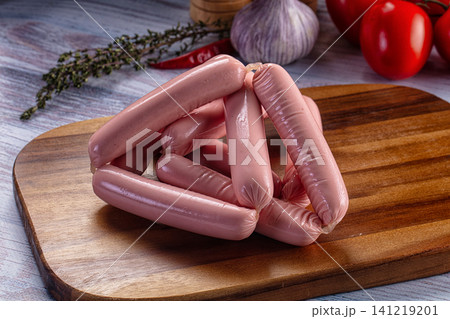 Raw sausages on wooden cutting board with garlic and tomatoes Raw sausages on wooden cutting board with garlic and tomatoes 141219201