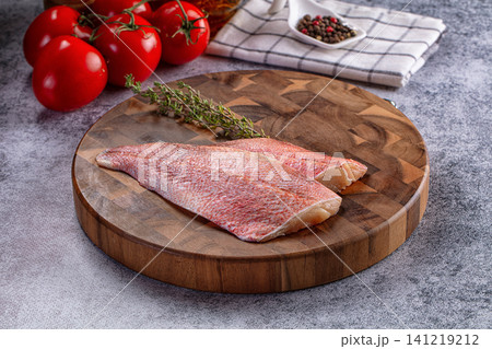 Raw sea perch fillet on wooden cutting board with tomatoes and thyme 141219212