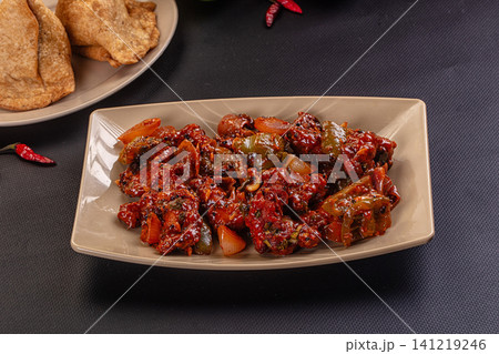 Spicy chicken curry with peppers and onions served on beige plate with fried bread Spicy chicken curry with peppers and onions served on beige plate with fried bread 141219246
