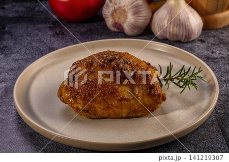 Appetizing roasted chicken thigh with crispy skin and rosemary on a ceramic plate Appetizing roasted chicken thigh with crispy skin and rosemary on a ceramic plate 141219307