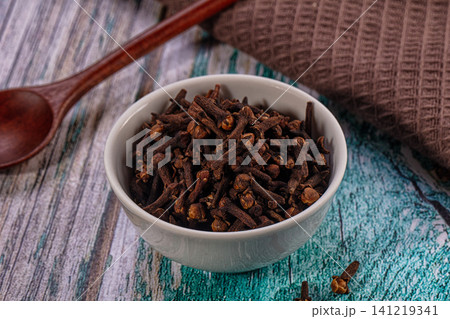 Clove spice in white ceramic bowl on rustic wooden surface with wooden spoon Clove spice in white ceramic bowl on rustic wooden surface with wooden spoon 141219341