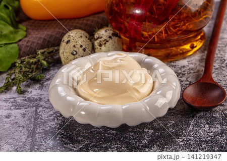 Creamy mayonnaise in white ceramic bowl with quail eggs and herbs on rustic surface Creamy mayonnaise in white ceramic bowl with quail eggs and herbs on rustic surface 141219347