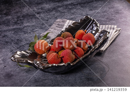 Fresh lychee fruits in black ceramic bowl on dark textured surface Fresh lychee fruits in black ceramic bowl on dark textured surface 141219359